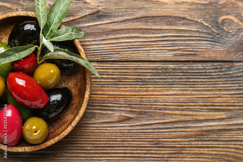 Plate with different kinds of tasty olives on wooden background