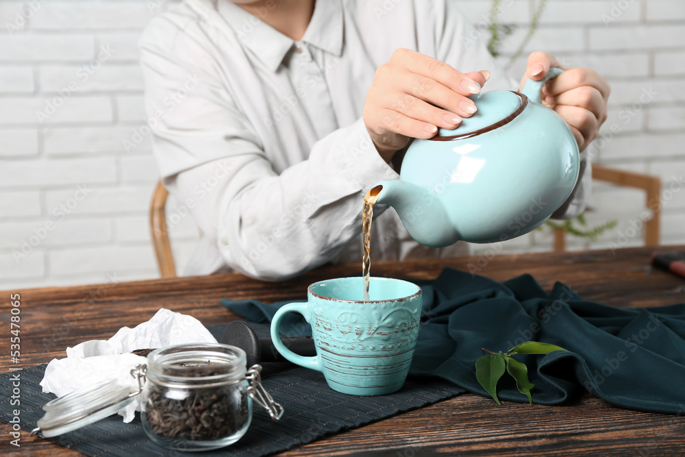 女人在木桌上从壶里倒普洱茶，特写