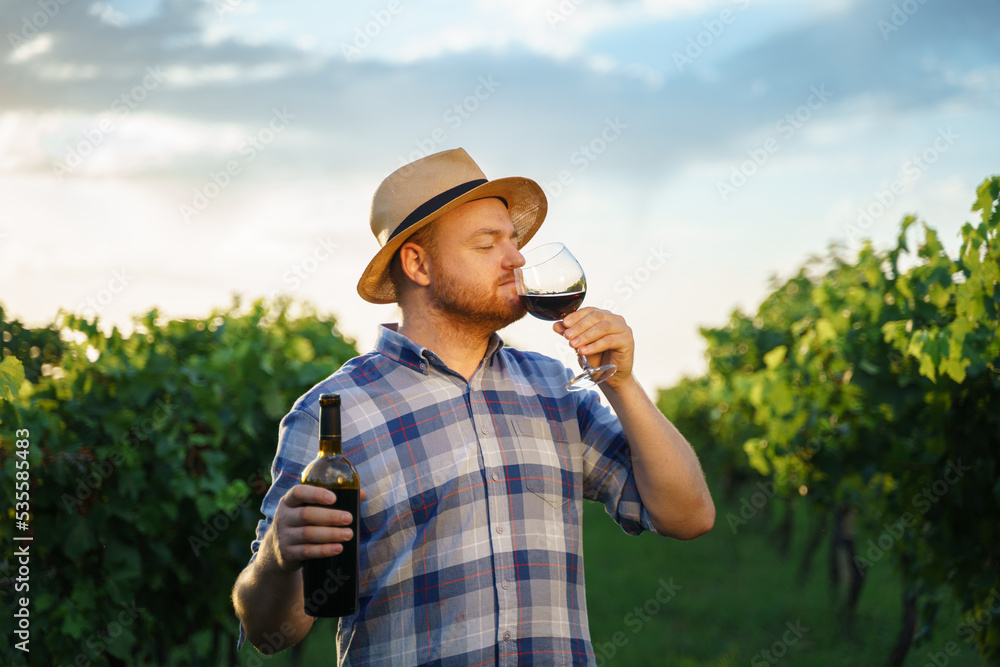 Authentic shot of happy successful male winemaker is tasting a flavor and checking red wine quality 