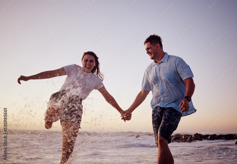 海滩上的水花飞溅，情侣和幸福的人在夏天日落时一起感受爱和乐趣。女孩