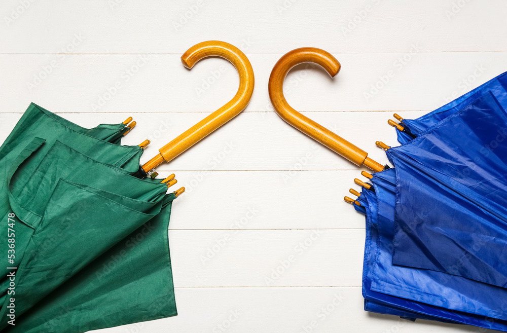 Stylish bright umbrellas on white wooden background, closeup