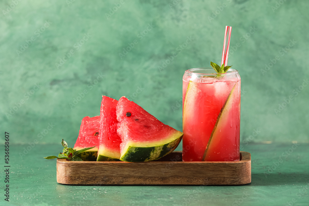 Wooden board with glass of cold watermelon fresh on green background