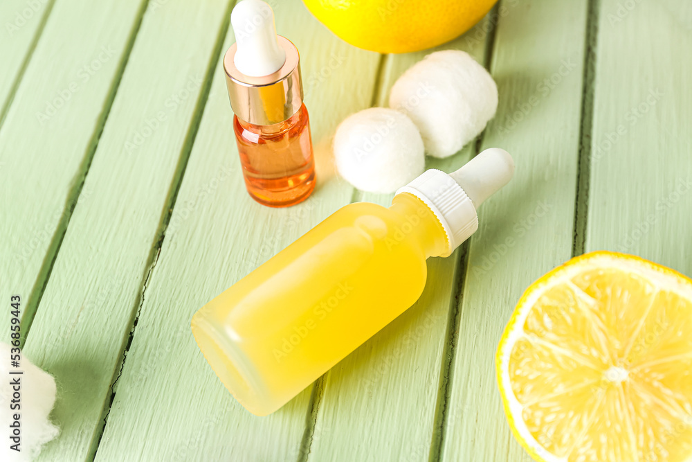 Bottles of citrus serum on color wooden background