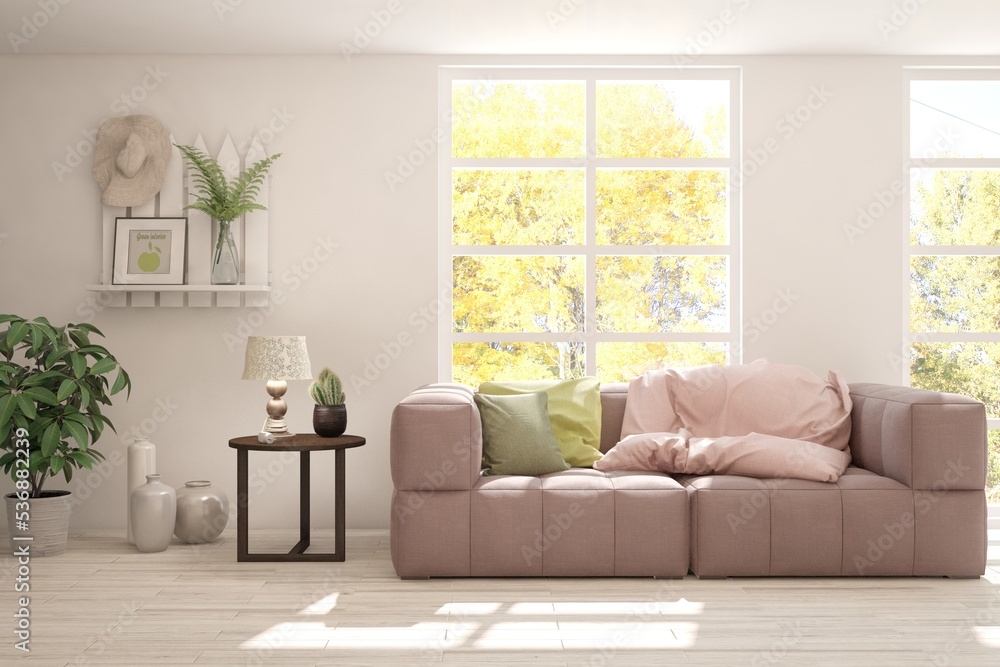 Stylish room in white color with sofa and autumn landscape in window. Scandinavian interior design. 