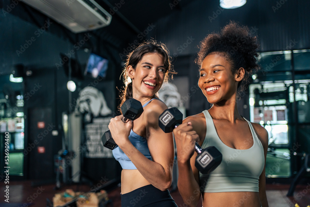 Latino and African sport woman exercising and build muscle in stadium. 