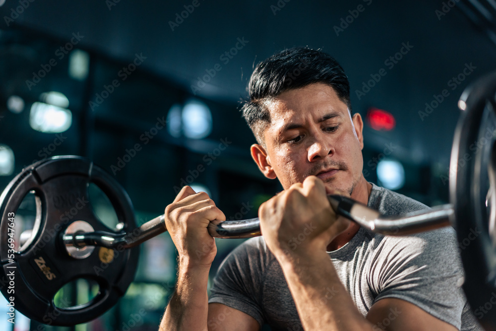 Caucasian sportsman slowly lift up weight machine barbell in stadium.