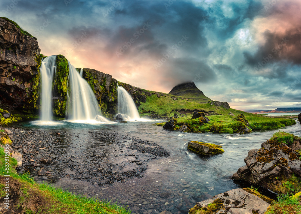 Landscape of sunset over Kirkjufell mountain with Kirkjufellsfoss waterfall and colorful pileus clou