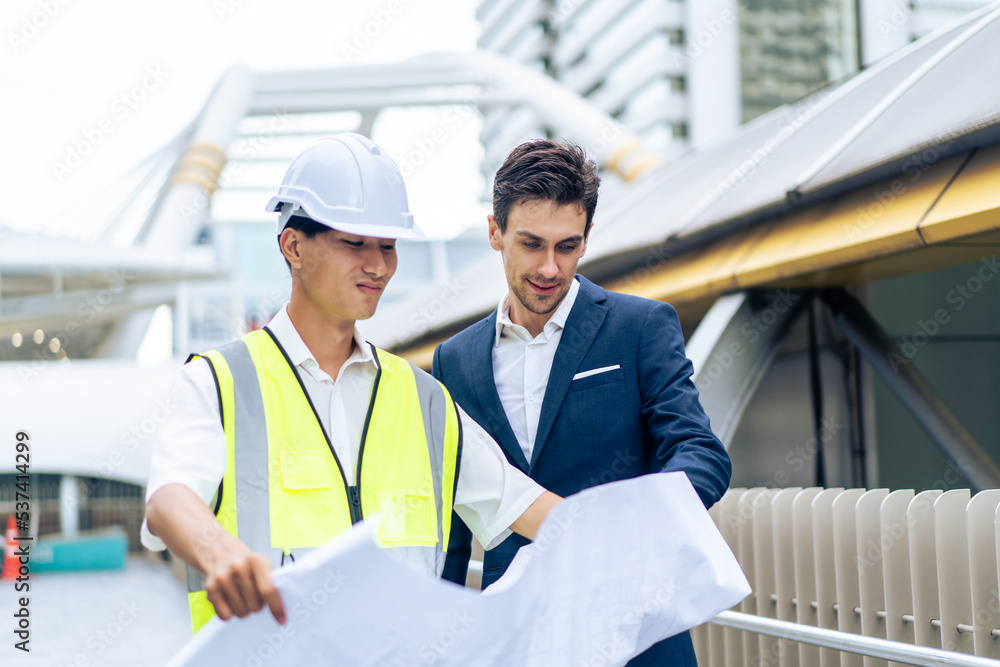 Caucasian businessman and Asian worker working in outdoors in city. 