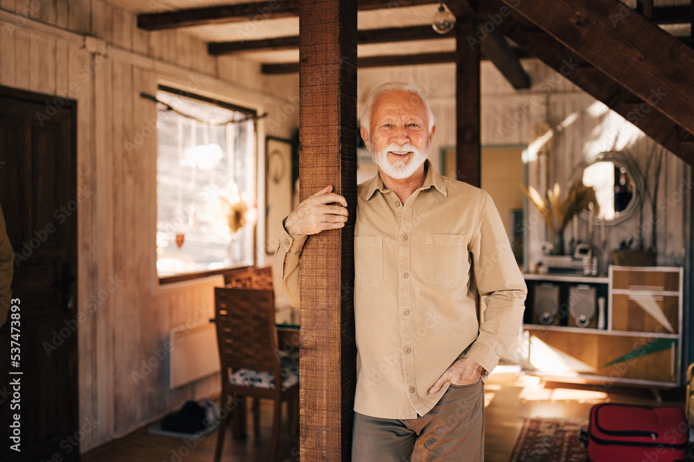 Portrait of a mature man, holding a wooden post, standing and smiling for the camera.