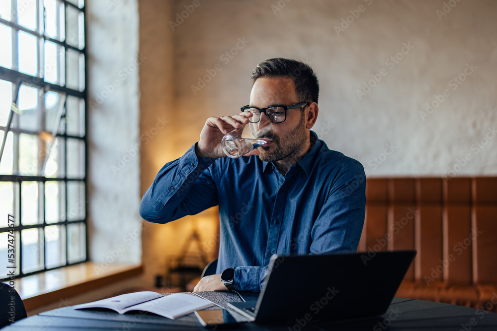 一个商人在办公室上网工作时喝了一杯水。