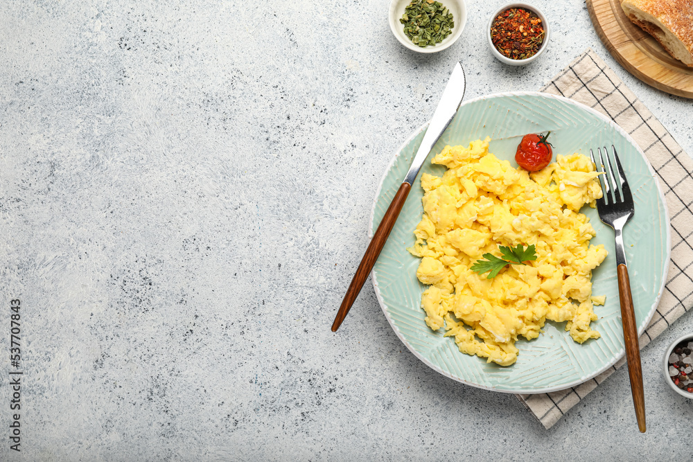 Plate of tasty scrambled eggs and spices on light background