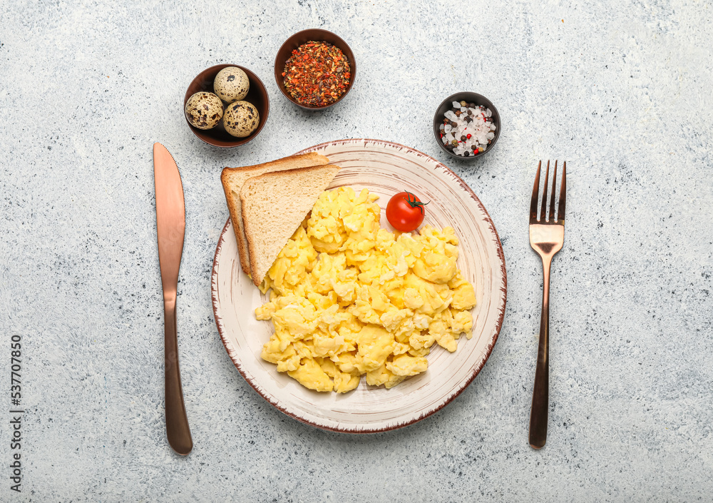 Plate of tasty scrambled eggs, bread and spices on light background