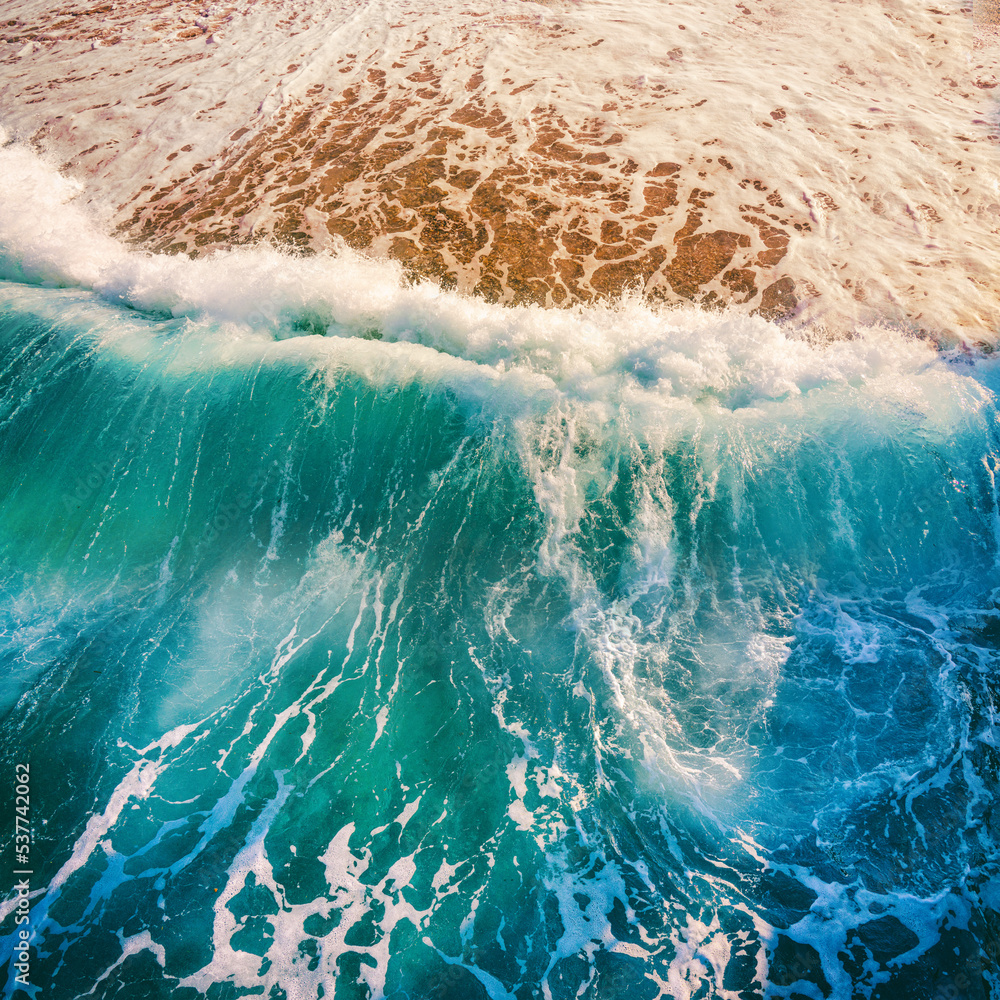 Natural beauty of marine nature - transparent turquoise waves illuminated by sun roll on a golden sa