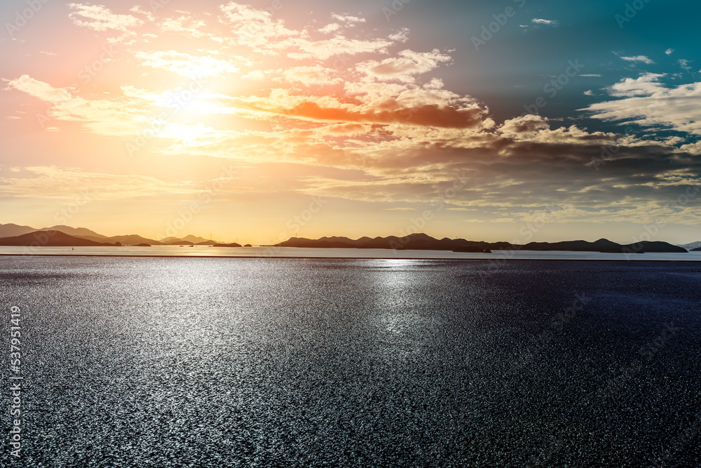 Asphalt road and lake with mountain nature landscape at sunrise