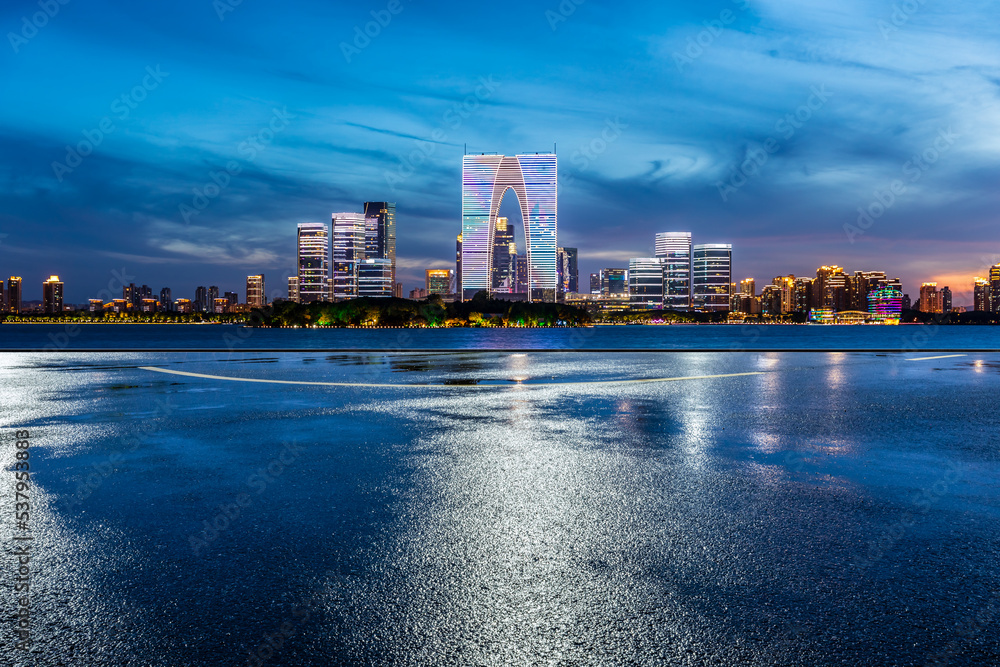 中国苏州夜晚空旷的道路和城市天际线，现代建筑。