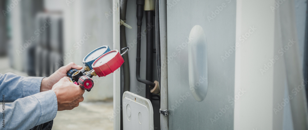 Mechanic  air conditioner technician is using a manifold gauge to check the refrigerant in the syste