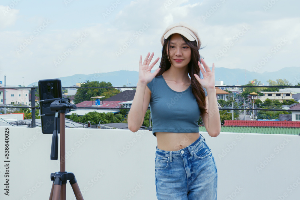 Young Asian woman created her dancing video by smartphone camera on rooftop outdoor at sunset. To sh