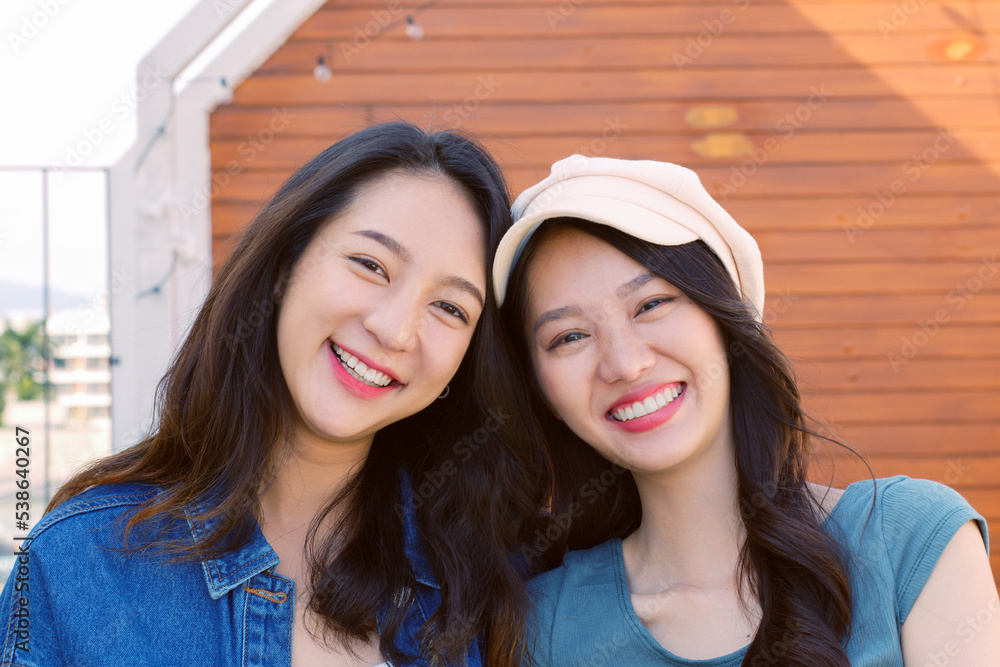 Cute young Asian woman with friends expressing positive emotion, smiling and laughing to camera outd