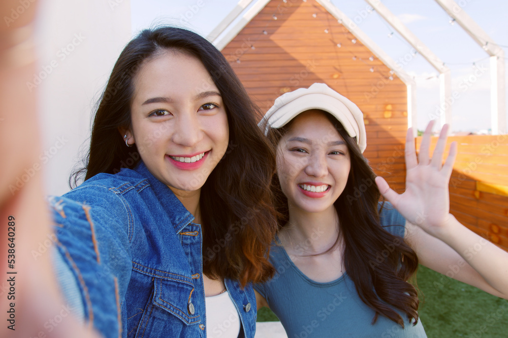 POV of young asian woman with friend holding phone  selfie making video call