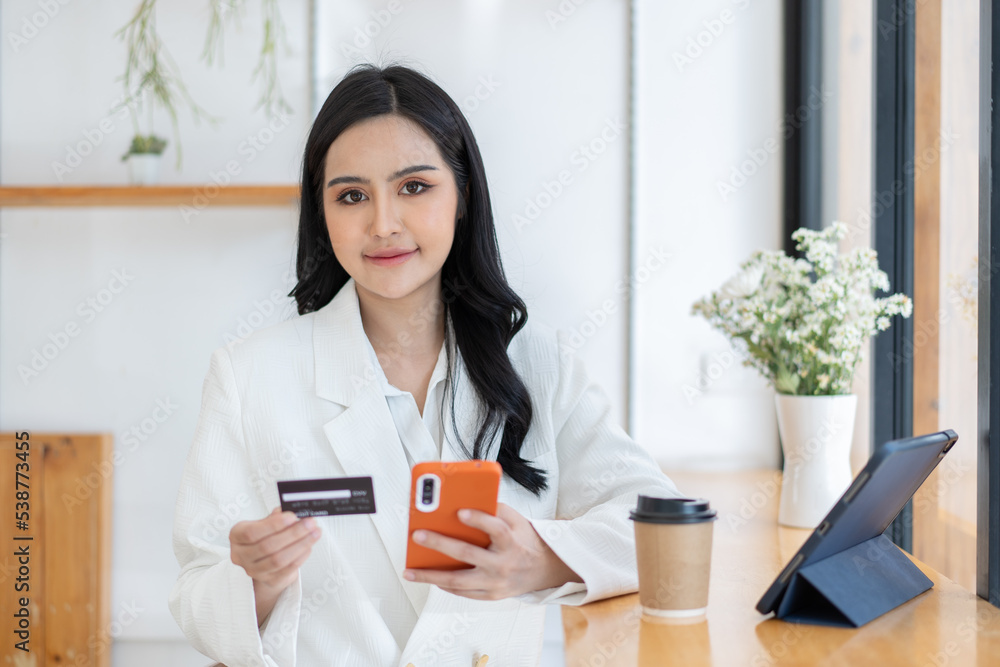 Young woman holding credit card and using laptop computer.