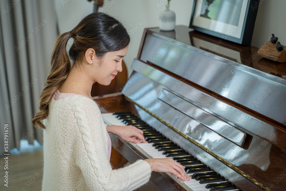 亚洲女钢琴家正在录音室里享受钢琴演奏。