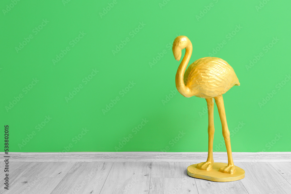 Golden flamingo near green wall in room