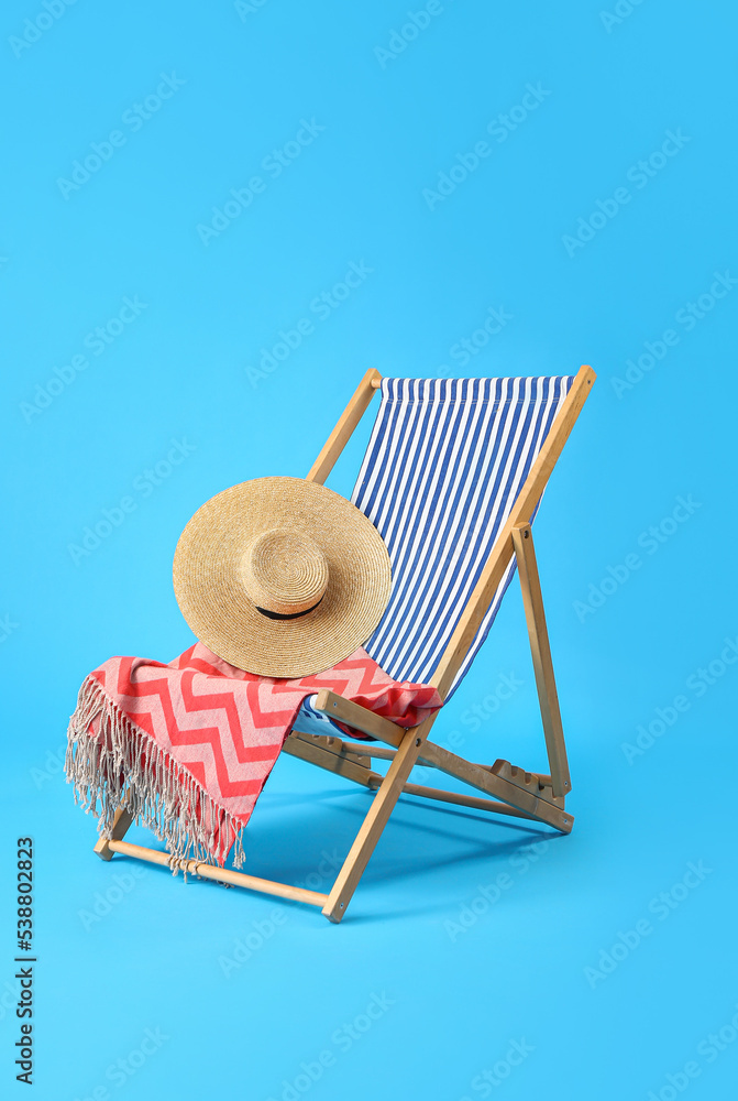 Deck chair and beach accessories on light blue background