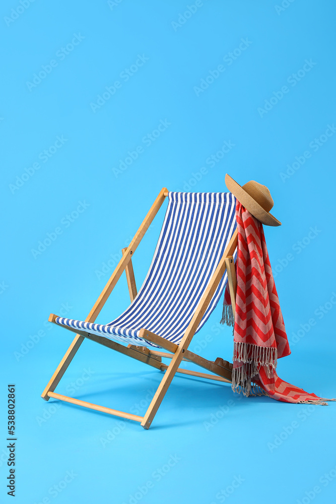 Deck chair and beach accessories on light blue background