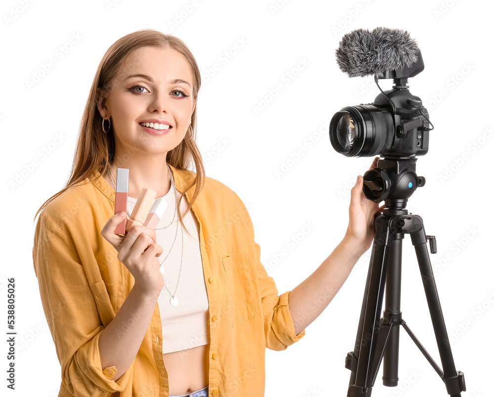 Young beauty blogger with lipsticks recording video on white background