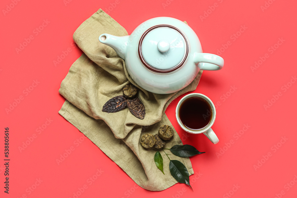 红色背景的干压普洱茶、杯子和茶壶餐巾