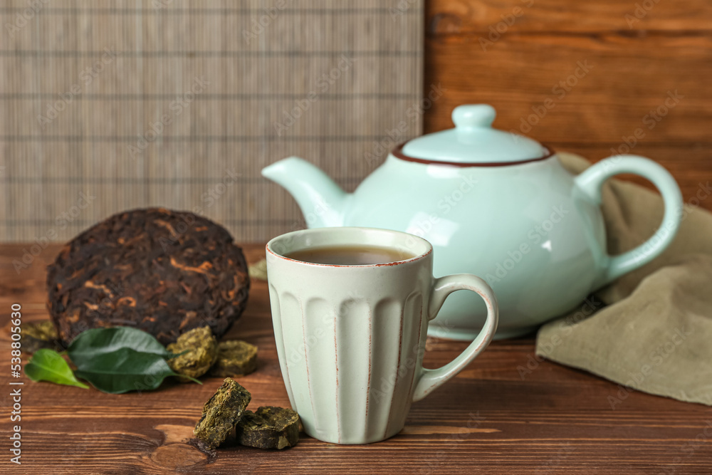 Dry pressed puer tea with cup on wooden table, closeup