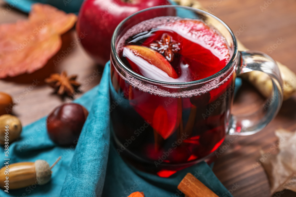 Cup with aromatic mulled wine on wooden table, closeup