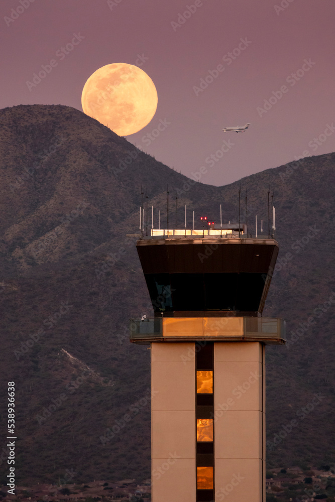 This large full moor rises over the McDowell Mountaind range and the airport tower at Scottsdale, Ar