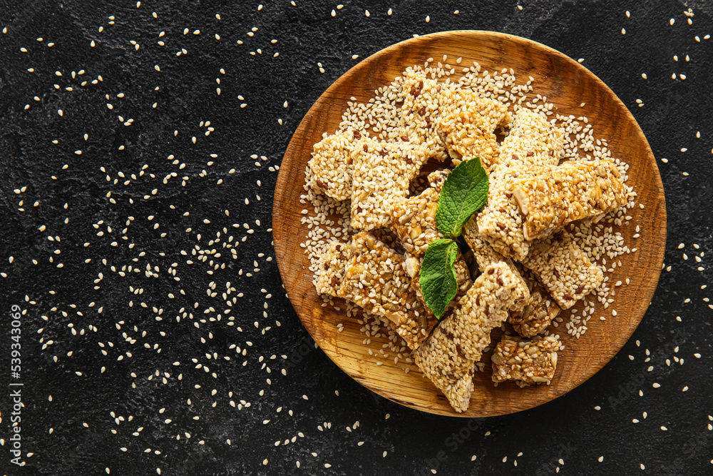 Plate with pieces of tasty sesame kozinaki on dark background