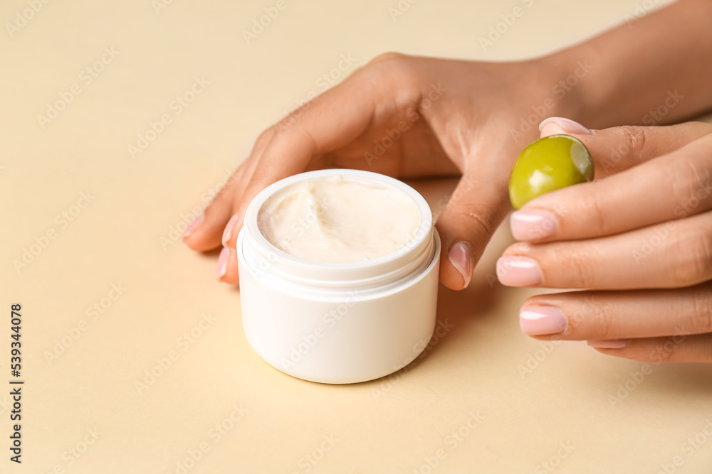 Female hands with jar of natural olive cream on color background, closeup