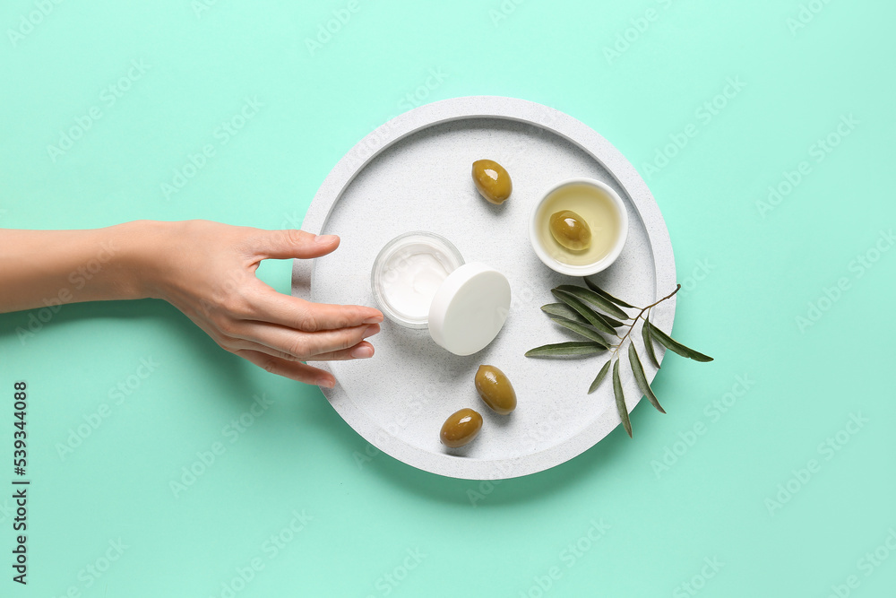 Female hand with jar of natural olive cream on color background