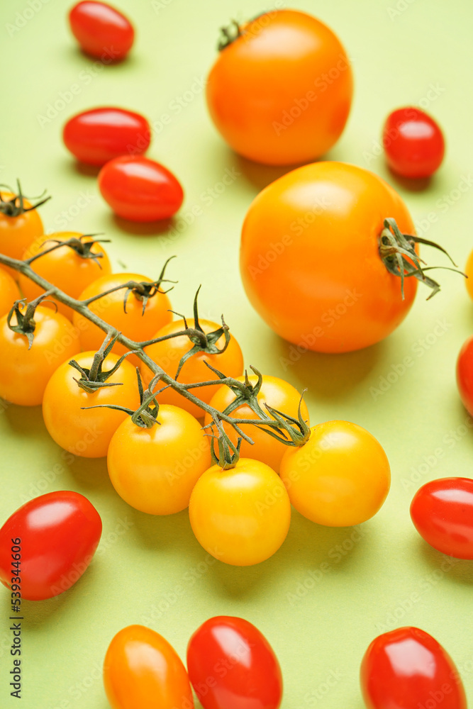 Different fresh tomatoes on green background, closeup