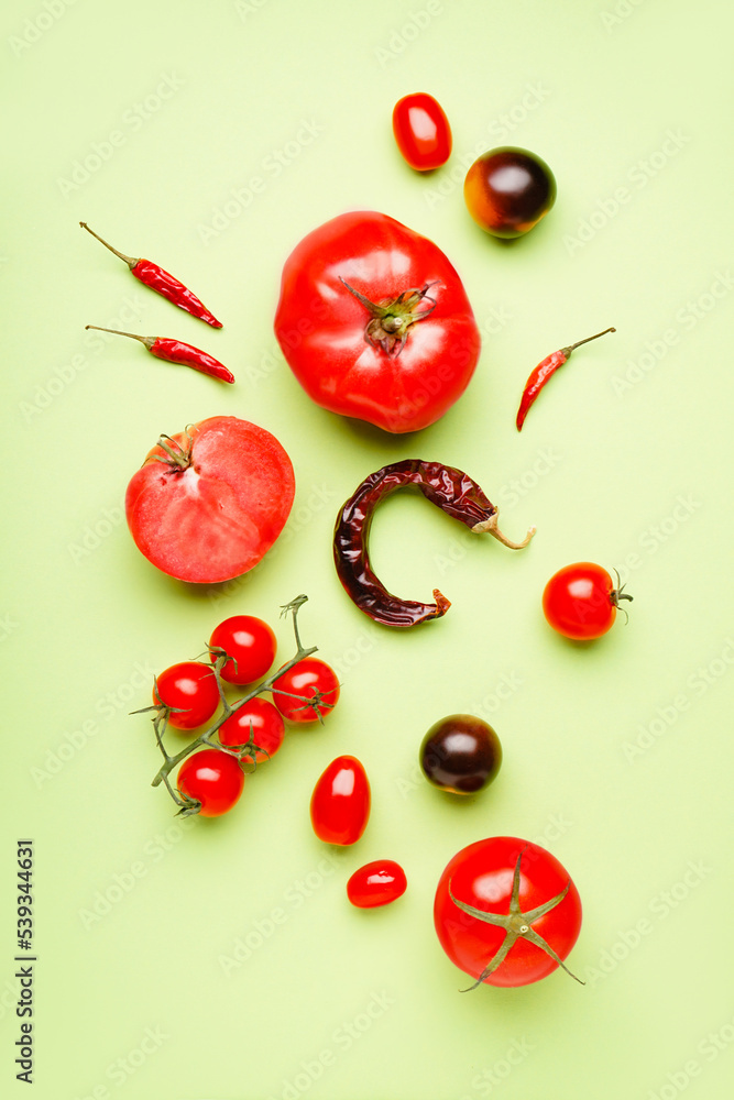 Composition with fresh tomatoes and dried chili peppers on green background