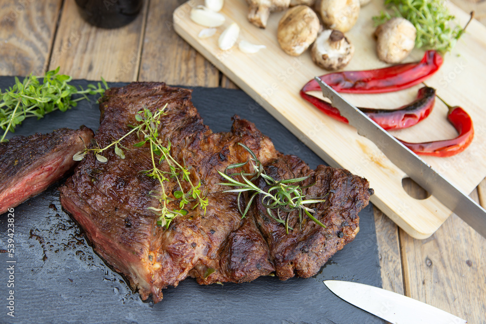 Grilled beef steak on wooden table top. Healthy food concept. Beef cut outdoors, garden kitchen, bbq