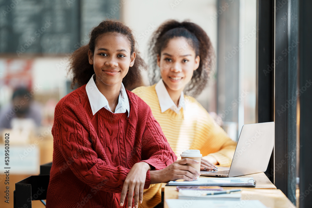 Image of happy woman using laptop while sitting at cafe. Young african american woman sitting in a c