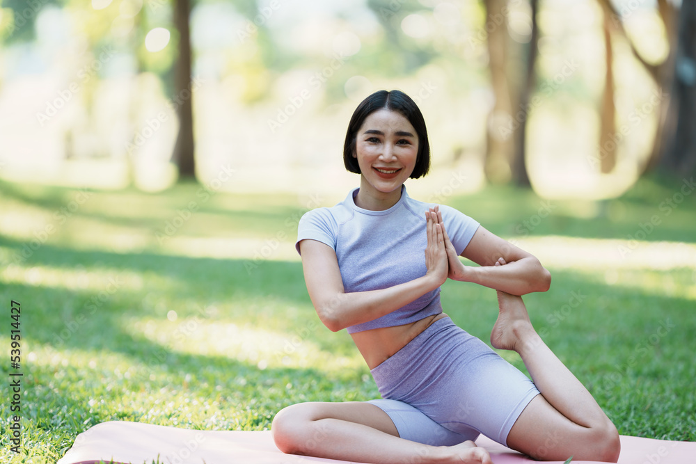 美丽的年轻亚洲女子在公园里练习瑜伽。