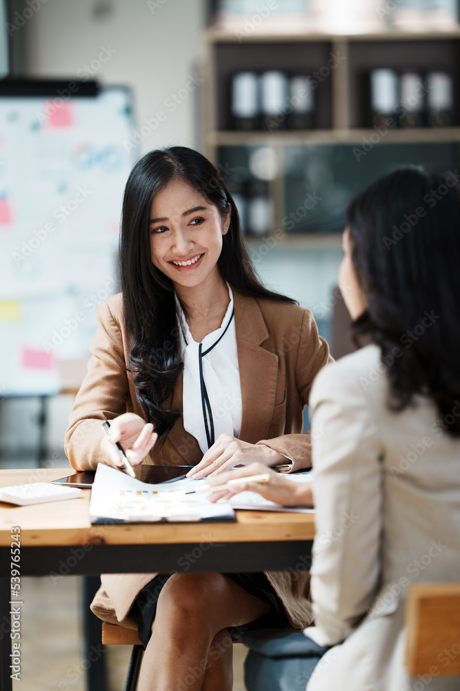  2 Young smiling businesswomen having a discussion with CEO in the office.