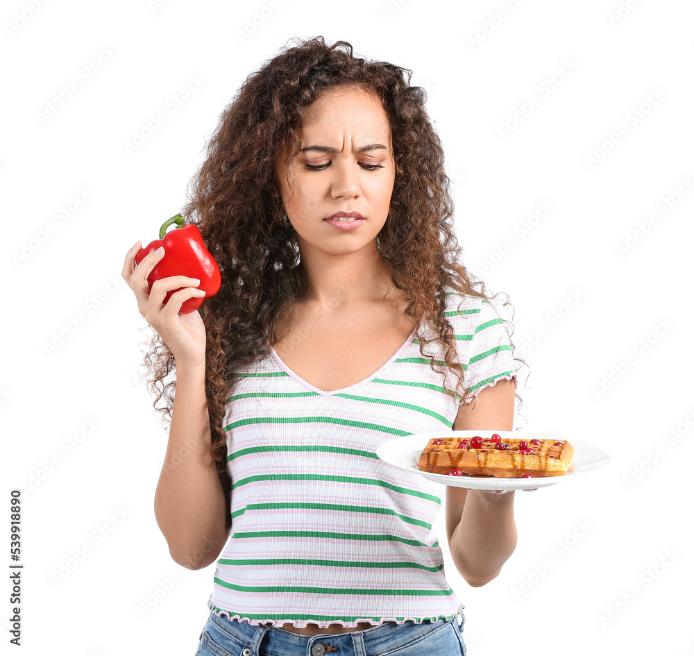 Young African-American woman with pepper and waffle on white background. Diet concept