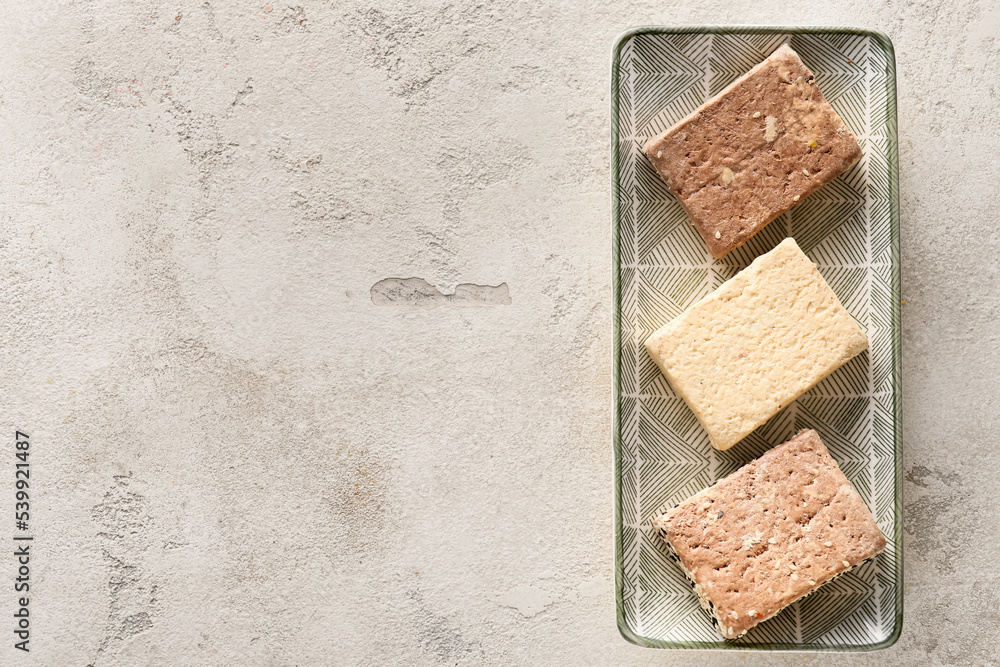 Plate with pieces of tasty sesame halva on light background