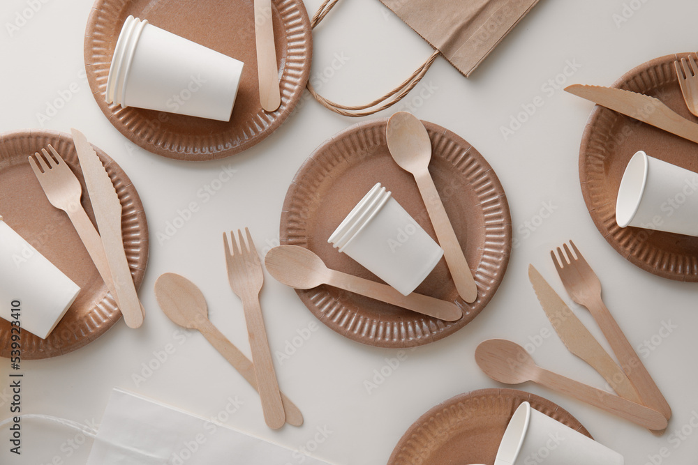 Eco tableware and paper bag on light background