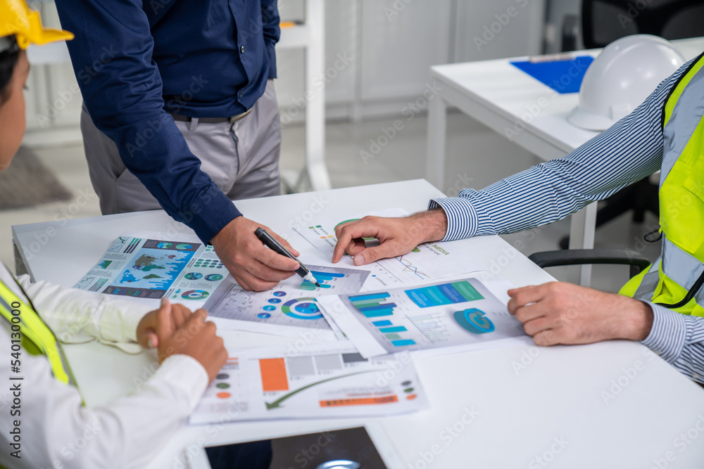 Engineers and competent employer discussing plans and blueprints together with tablet in the office.