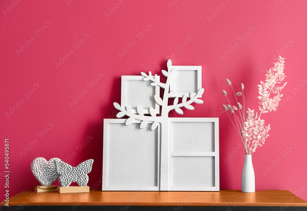 Family tree with photo frames and decor on table near red wall