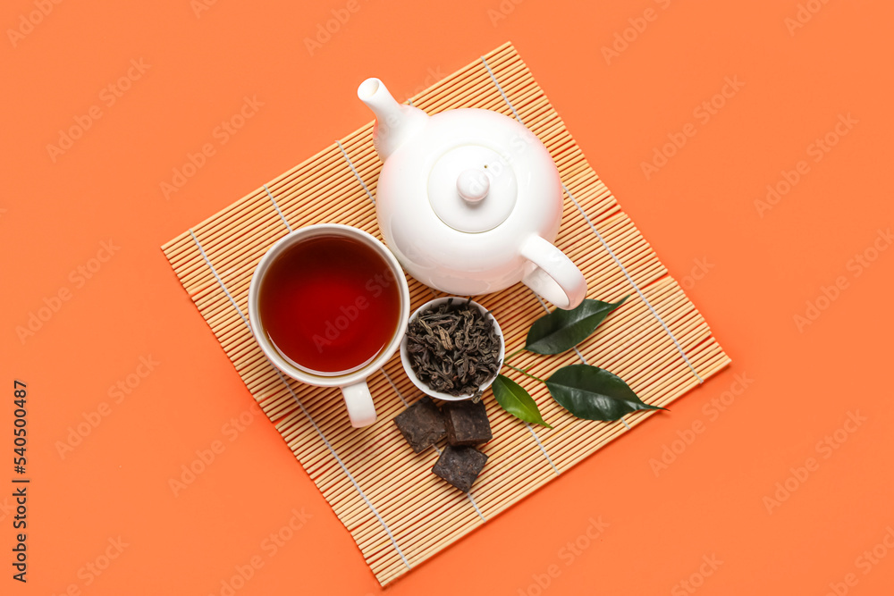 竹垫，橙色背景上有一碗干普洱茶、杯子和茶壶