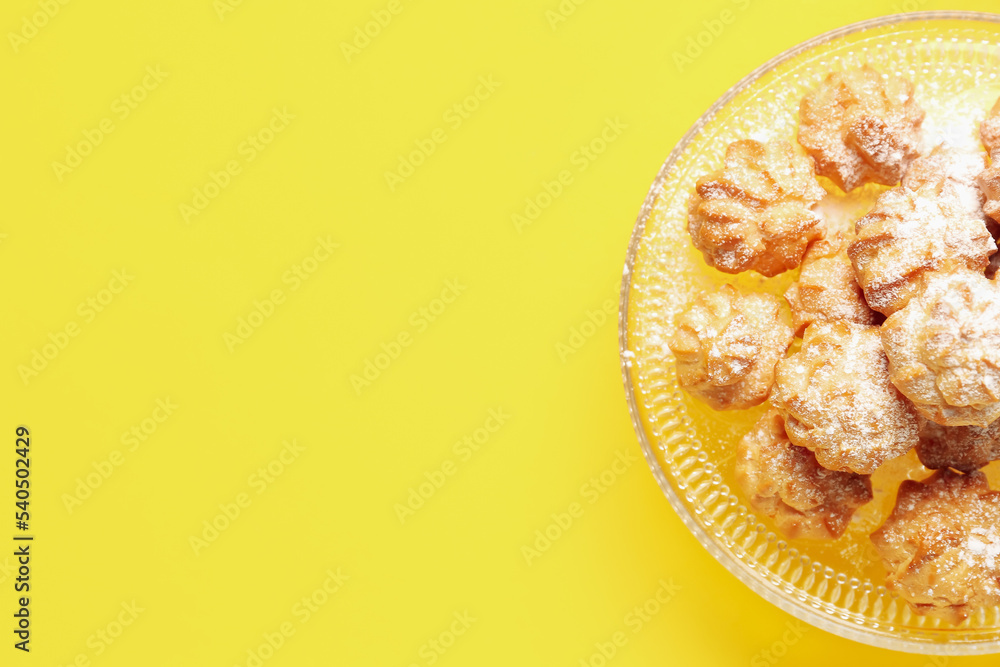 Dessert stand with delicious eclairs on yellow background