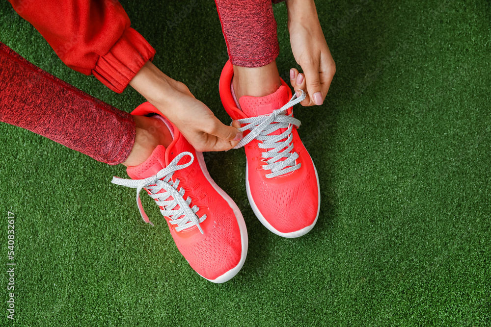 Woman tying shoe lace on green background, closeup